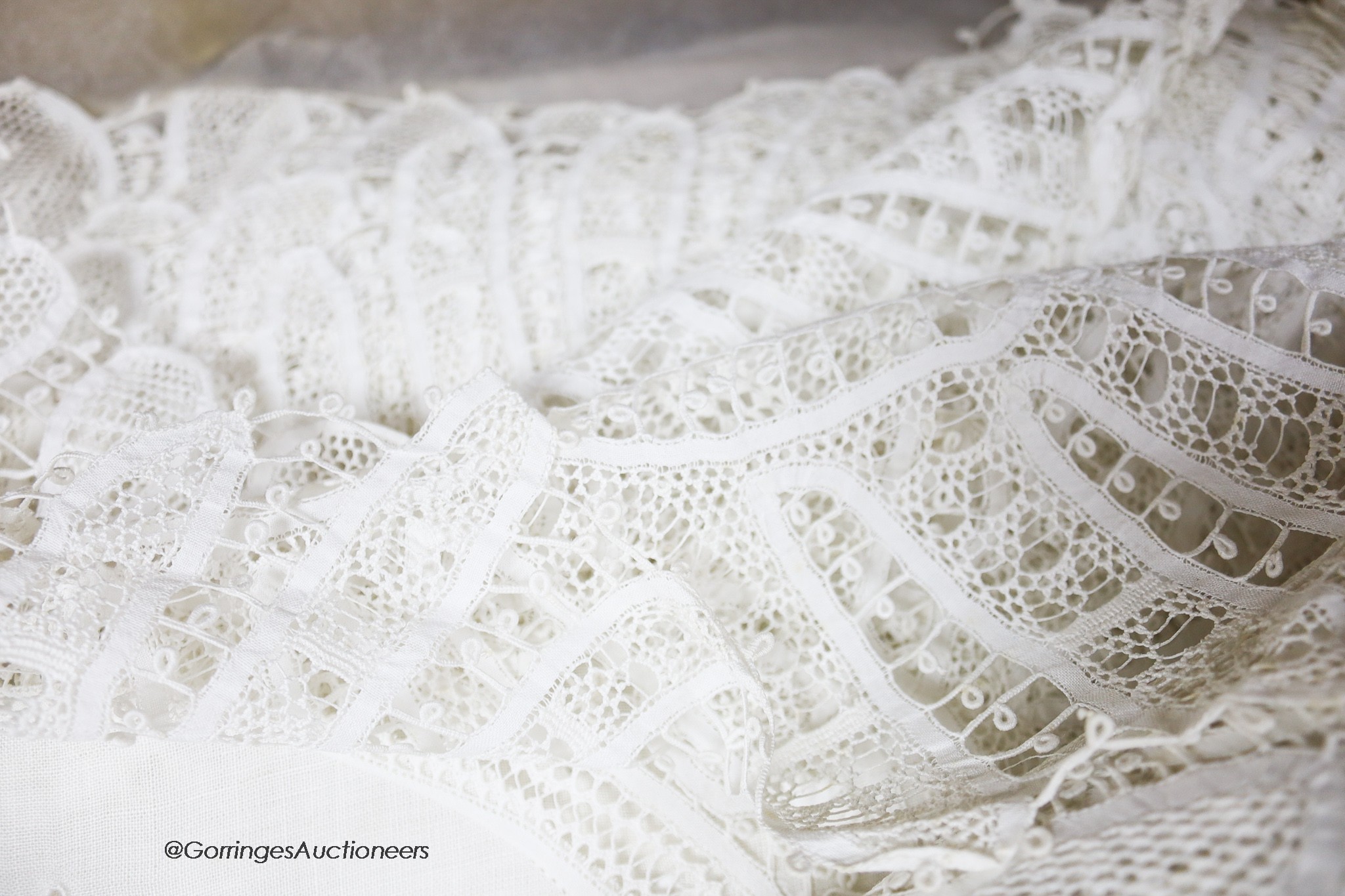 A finely worded tapelace and cutwork white tablecloth with matching serviettes and a similar ecru table cover